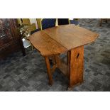 An oak Arts an Crafts drop leaf table, the block side panels with pierced heart design supporting