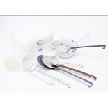A collection of enamelled kitchenware, including various pierced ladles, a colander, a