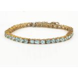 A contemporary 9ct gold blue apatite line bracelet, the oval mixed cut claw set blue gem stones with