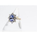 An 18ct gold Ceylon sapphire and diamond cluster ring, the oval mixed cut stone in four claw setting