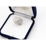 A continental white 18ct gold diamond bombe shaped ring, brilliant cuts in raised pave setting,