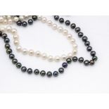 Two opera length uniform knotted strings of cultured pearls, one in black, 74cm, the other in cream,