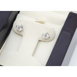 A pair of diamond stud earrings, the brilliant cuts in white claw setting on yellow screw backs with