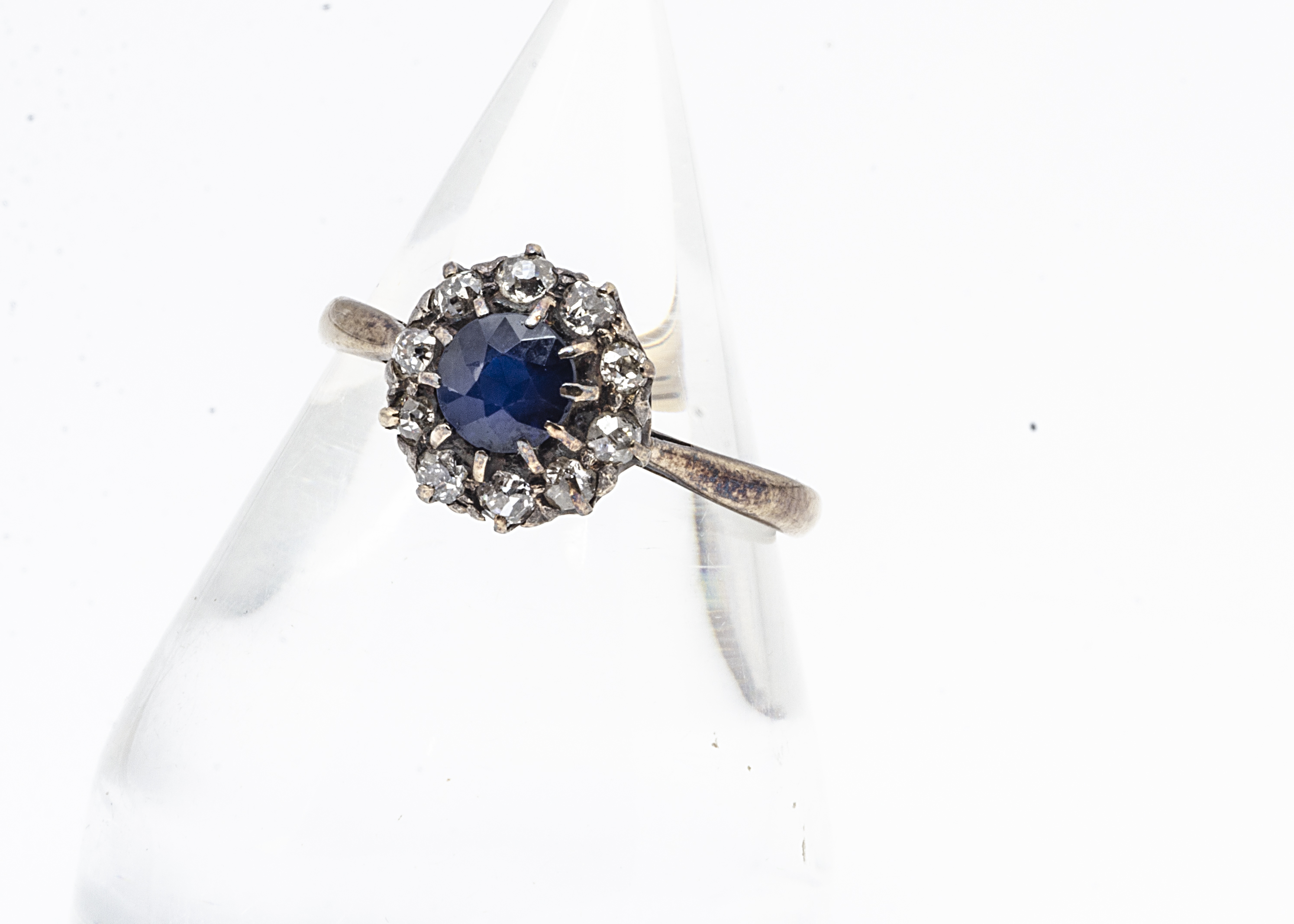 A sapphire and diamond cluster ring, the circular cut claw set sapphire surrounded by old cut