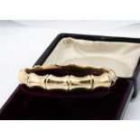 A 9ct gold bamboo effect hinged bangle, with box clasp and safety chain, 6cm x 5.5cm, 15g, boxed