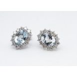 A pair of aquamarine and diamond white 18ct gold cluster earrings, central oval claw set aquamarines