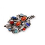 An Arts and Crafts silver and gem set floral brooch, set with two oval cabochons of Baltic amber,