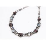 An Arts and Crafts gem set choker necklace, the stylised circular floral rubellite set links