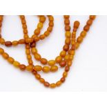 An opera length string of uniform oval butterscotch amber beads, 88cm long together, 9.5mm diameter,