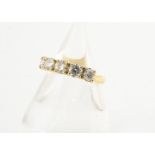 An 18ct gold diamond set five stone ring, the brilliant cuts in claw settings on a thick yellow gold