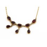 A 9ct gold garnet fringe necklace, the oval cut garnets supporting three tear cut pendants in claw