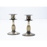A pair of early George V silver and ivory candlesticks, circular hammer beaten bases with carved