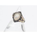 An Arts and Crafts silver and gold moonstone set signet ring, the cabochon oval moonstone within a