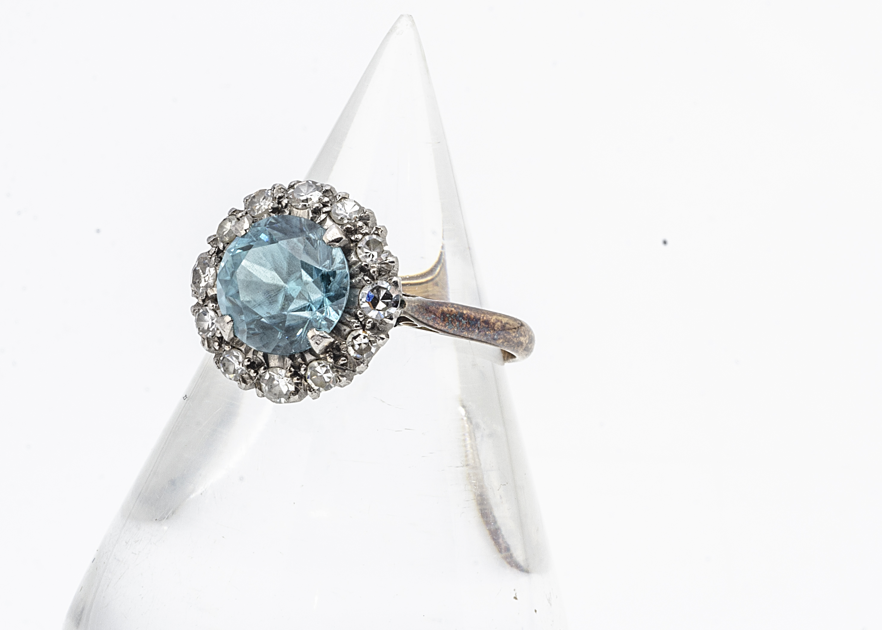 A zircon and diamond cluster dress ring, the circular mixed cut blue zircon in a four claw setting