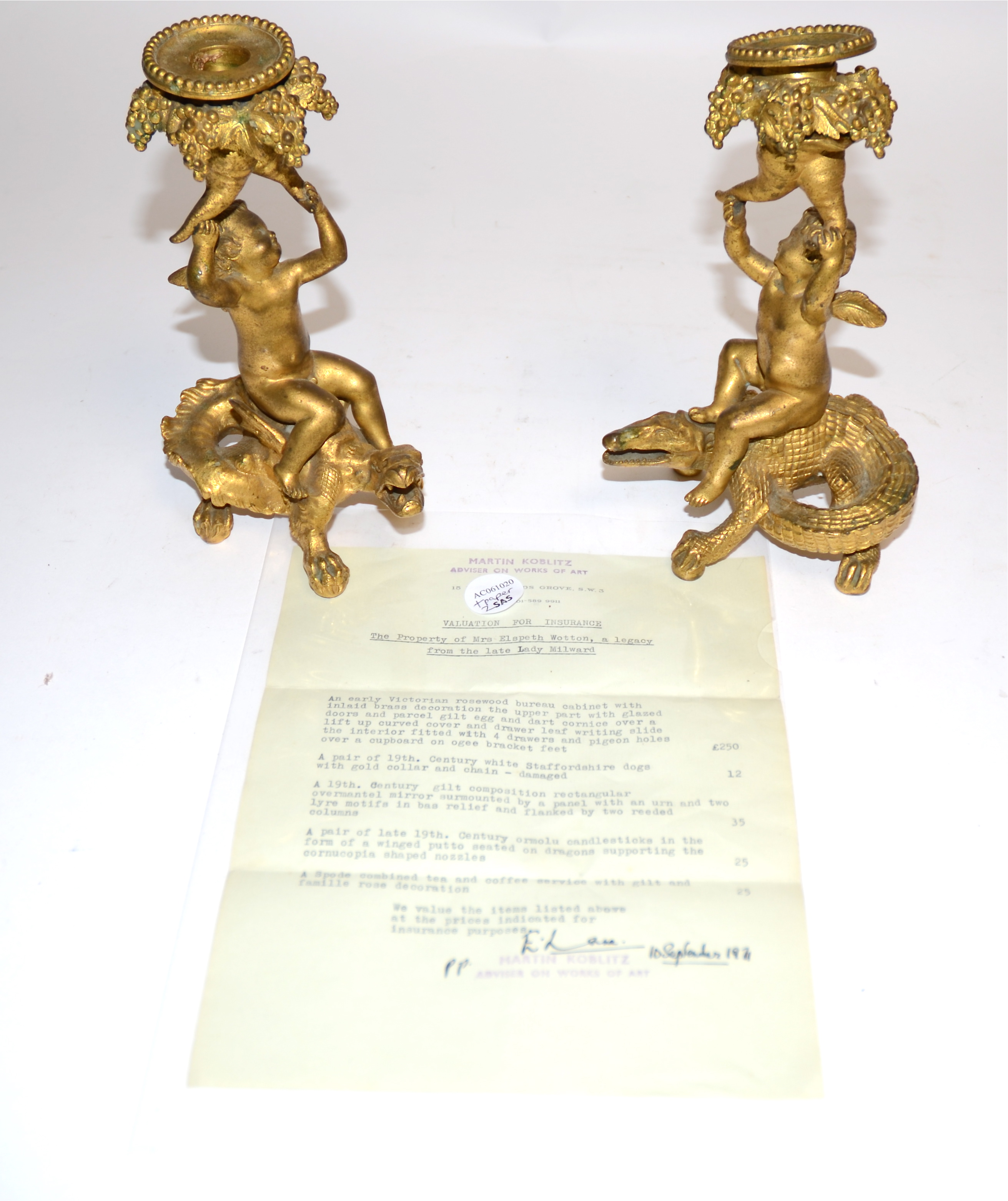 A pair of 19th Century ormolu candlestick holders, each with a putto supporting a cornucopia of