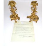 A pair of 19th Century ormolu candlestick holders, each with a putto supporting a cornucopia of