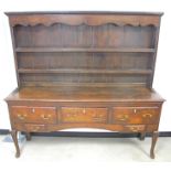 An antique oak dresser, enclosed panelled back with shaped frieze and two fixed shelves, five drawer
