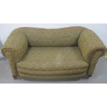 A late 19th Century two seater drop end Chesterfield settee, upholstered in a floral fabric with