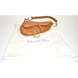 A Christian Dior tan coloured kidney shaped bag, the strap attached at either end to metal 'C' 'D'