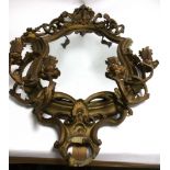 An early 20th Century gilt painted mirror with floral candlestick holders, taking the form of four
