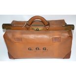 A tan leather Gladstone bag, bearing the initials 'G.O.G', 62cm x 30cm x 30cm