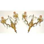 A pair of gilt metal and glass wall lights, each with two branches supporting floral bowls,