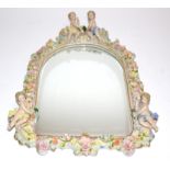 An early 20th Century wall mirror with porcelain surround, surmounted by two cherubs, and with a