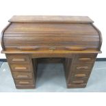 An Edwardian oak roll top desk, C shape tambour front revealing fitted interior above twin pedestals