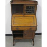An Arts and Crafts Liberty and Co oak students bureau, gallery top above a lead glazed cupboard
