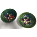Two Moorcroft Pottery bowls, both with tube lined decoration on green grounds, one with iris or