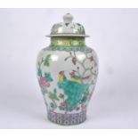 A Chinese covered jar with Famille rose decoration, with lotus panels, rising to a study of birds