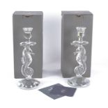 Two Waterford crystal candlesticks, the bowls raised and supported by figural seahorses, in original