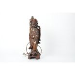A hardwood Chinese lamp, in the form of an Immortal holding a staff and peach, height excluding