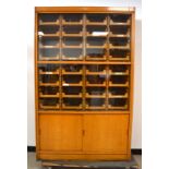 A 1930's oak haberdasher's cabinet, fitted interior with 32 comb jointed drawers, four sliding glass