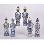 Six 20th Century Chinese figures in two groups, each figure with long plaited hair, caps and blue