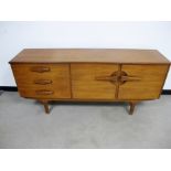A Mid - Century teak veneered sideboard, double cupboard to one side and three drawers to the other,