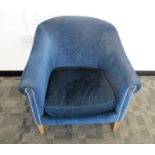 A contemporary tub arm chair, upholstered in a blue fabric with metal studding, raised on square