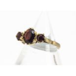 A three stone 9ct gold garnet dress ring, ring size R, 2.1g