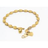 A continental yellow metal bracelet, of tear drop link design with heart and bell charm, marked