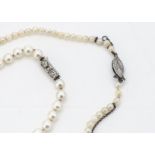 A string of uniform cultured pearls, the knotted strung white pearls with a pink overtone on an