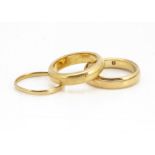 A 22ct gold court shaped wedding band, ring size I, another example ring size K 1/2, and a thin band