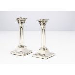 A pair of George V silver filled candlesticks by Thomas Bradbury & Sons, square bases with