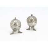 A pair of late 19th Century Indian white metal pepper pots, spherical with half dome covers and with