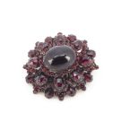 A Bohemian garnet foil back oval brooch, with central oval cabochon in claw settings surrounded by a