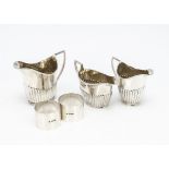 Three Victorian and George V silver helmet shaped milk jugs, together with a pair of silver napkin