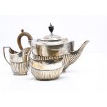 An associated Edwardian and later three piece silver tea set, all helmet shaped with fluted