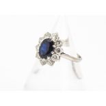 A sapphire and diamond 18ct white gold cluster ring, the oval mixed cut sapphire in claw setting