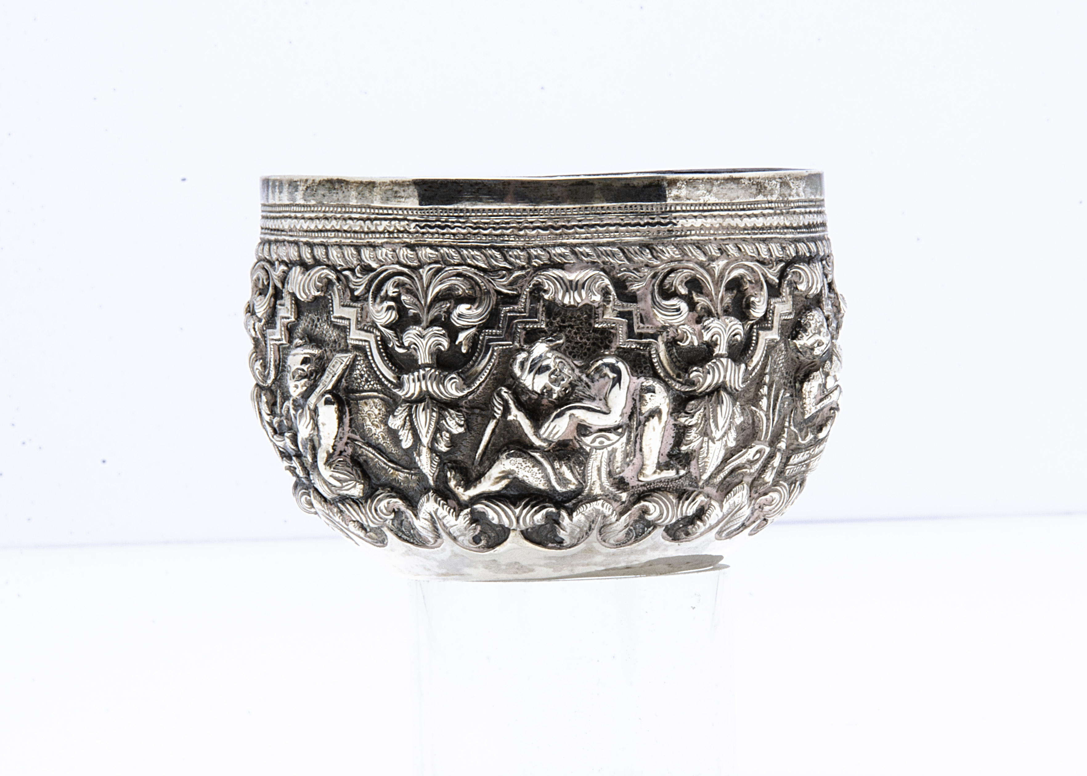 A small Burmese silver bowl, 9cm diameter, 3.6ozt, having raised design of figures in ornate