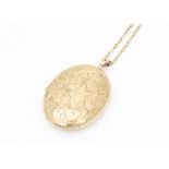 A 9ct gold oval locket with scroll engraved front, on an oval linked chain, 40cm together, 22g