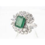 An impressive emerald and diamond cocktail ring, the central emerald cut in four claw setting